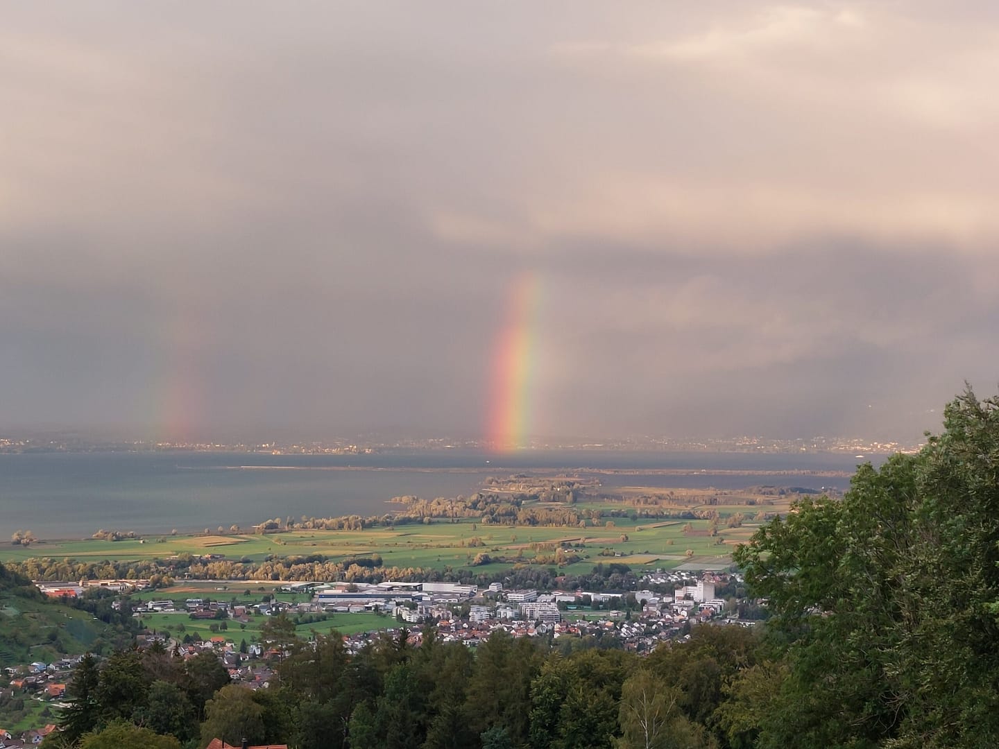 Blick auf das Rheintal mit einem leuchtenden Regenbogen, der durch dunkle Wolken bricht – Symbol für Klarheit und Neuausrichtung nach innerem Wandel.