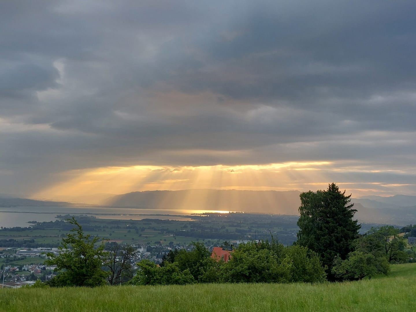 Goldene Sonnenstrahlen brechen durch dunkle Wolken und tauchen die Landschaft in sanftes Licht – ein Symbol für Klarheit nach innerem Wandel.