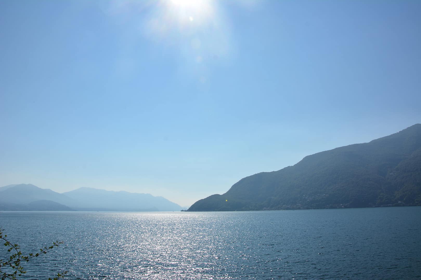 Sonne über dem Lago Maggiore mit glitzerndem Wasser und Bergkulisse – Klarheit, Weite und Inspiration, passend zur Energie von Aquarius.