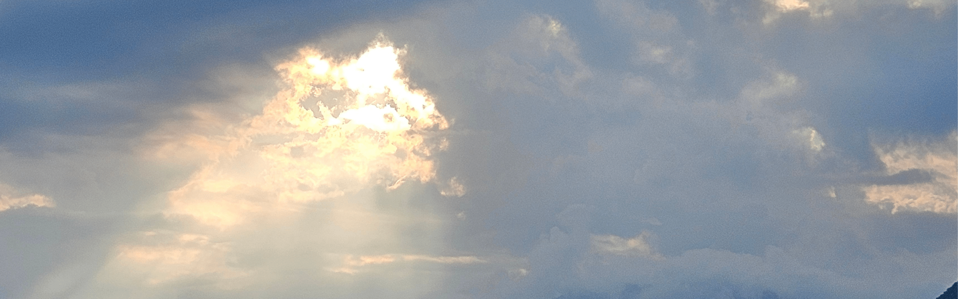 Licht bricht durch Wolken über Bergsilhouette – Symbol für Klarheit und Orientierung im Business