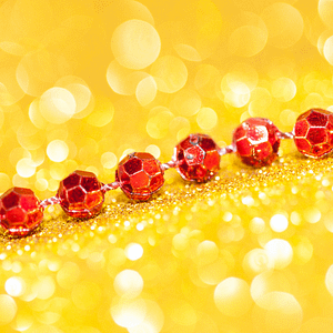 Rote funkelnde Perlenkette auf goldenem Glitzerhintergrund – Symbol für Energiefluss, Schutz und hochschwingende Business-Felder