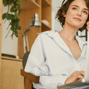 Lächelnde Frau mit Laptop in einem modernen, natürlichen Arbeitsumfeld – wirkt entspannt, inspiriert und fokussiert bei der Arbeit.