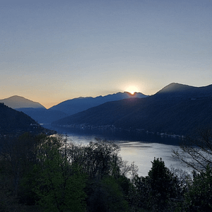 Sonnenaufgang über dem Lago di Lugano mit sanften Farben des Himmels – Symbol für Vision, Transformation und kosmische Orientierung im Business