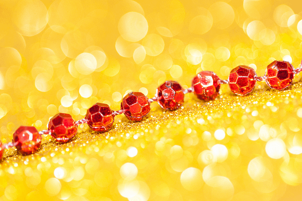 Rote funkelnde Perlenkette auf goldenem Glitzerhintergrund – Symbol für Energiefluss, Schutz und hochschwingende Business-Felder