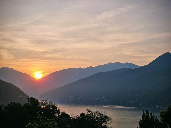 Sonnenaufgang über einem stillen See, umgeben von Bergen – Symbol für einen neuen Anfang und innere Klarheit - energetischer Reset