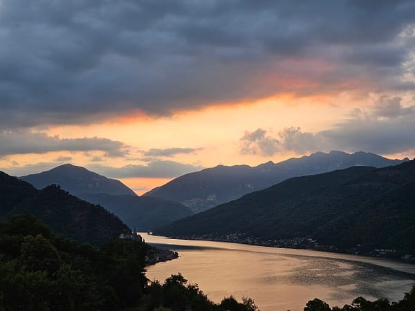 Sonnenaufgang über Berglandschaft und See, goldener Lichtstreifen zwischen dunklen Hügeln – Symbol für Neubeginn und innere Ausrichtung